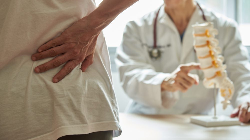 A,Male,Doctor,Explaining,Lumbar,Anatomy,To,Female,Patient,Complaining Lendenwirbelsäulenerkrankung als Berufskrankheit